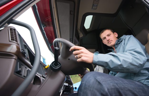 Truck driver sitting in cab of modern semi truck